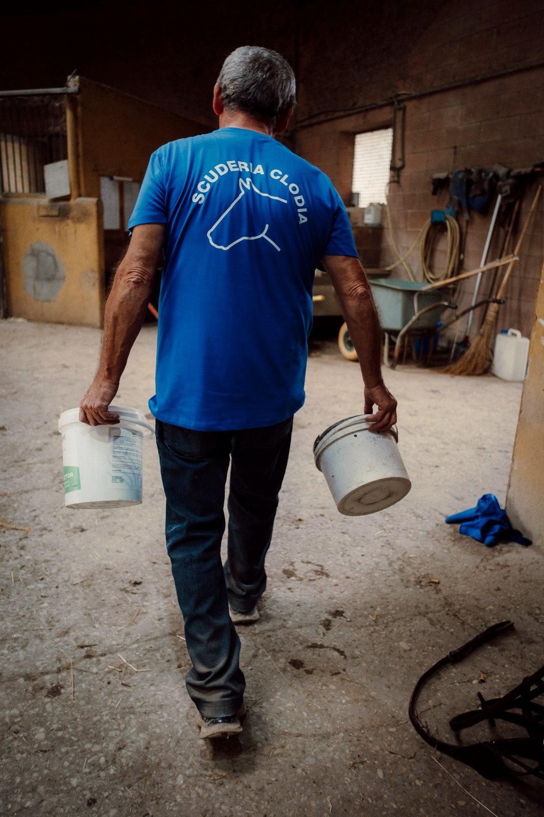 Un membro dello staff porta i secchi dell'alimentazione lungo la scuderia